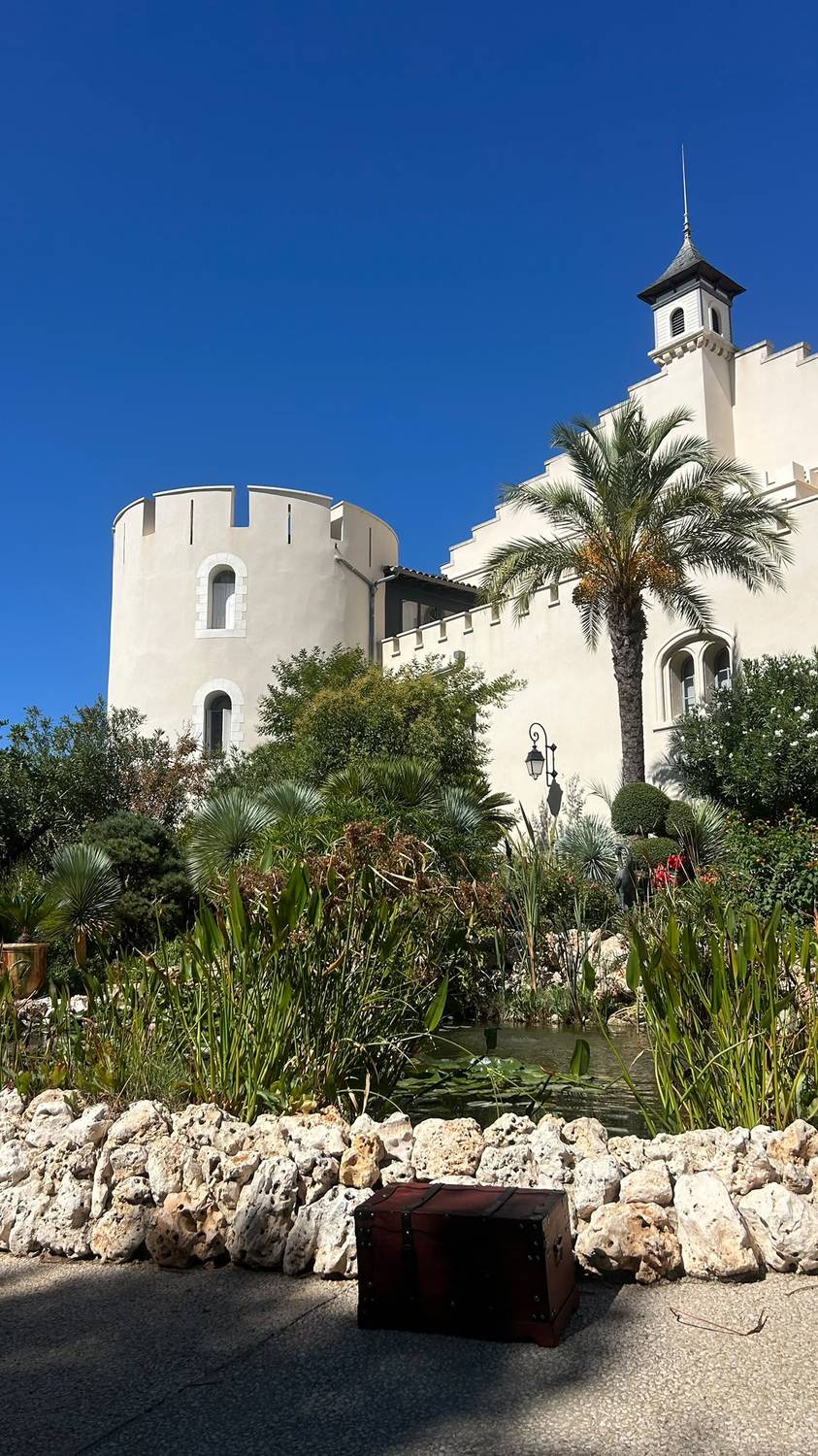 Tourelle et façade du Château l'Hermitage de Combas, avec une malle en bois façon coffre au trésor posée devant un bassin