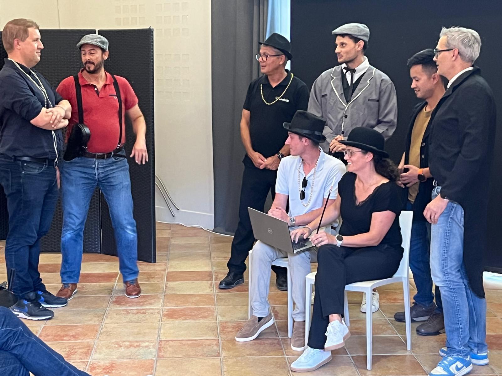 Une équipe en costumes années folles entre en scène pendant qu'en régie, à droite, l'ordinateur et le clap suivent le tournage