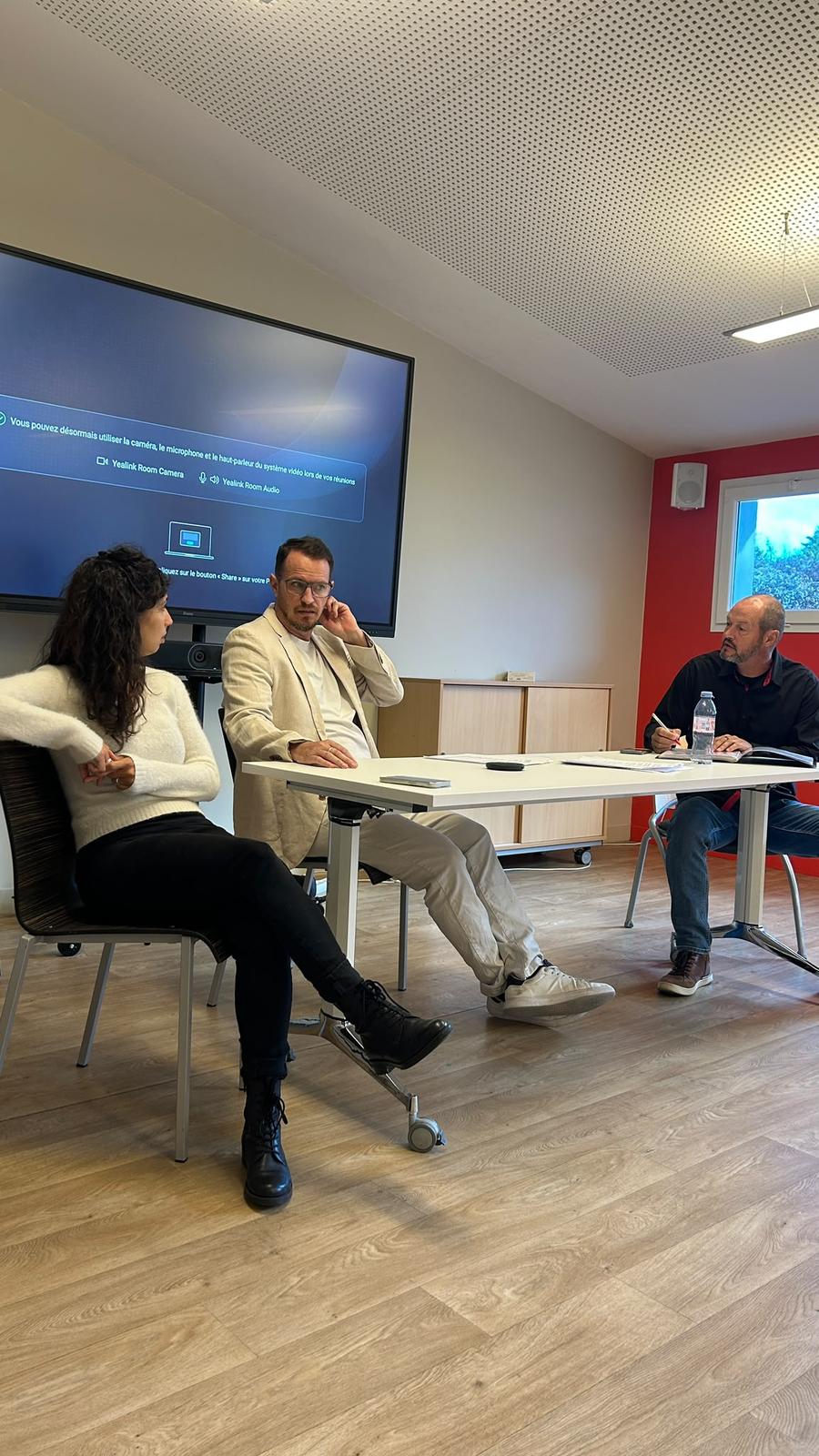 Un comedien de MEEUS s'adresse aux collaborateurs reunis en salle pour le theatre forum, ecran de visioconference en arriere-plan