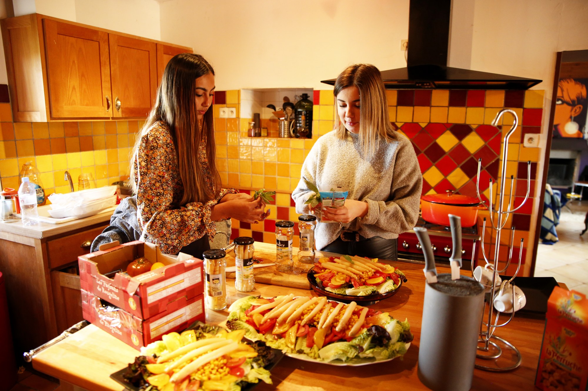 Deux participantes préparent le repas du groupe dans une cuisine conviviale.
