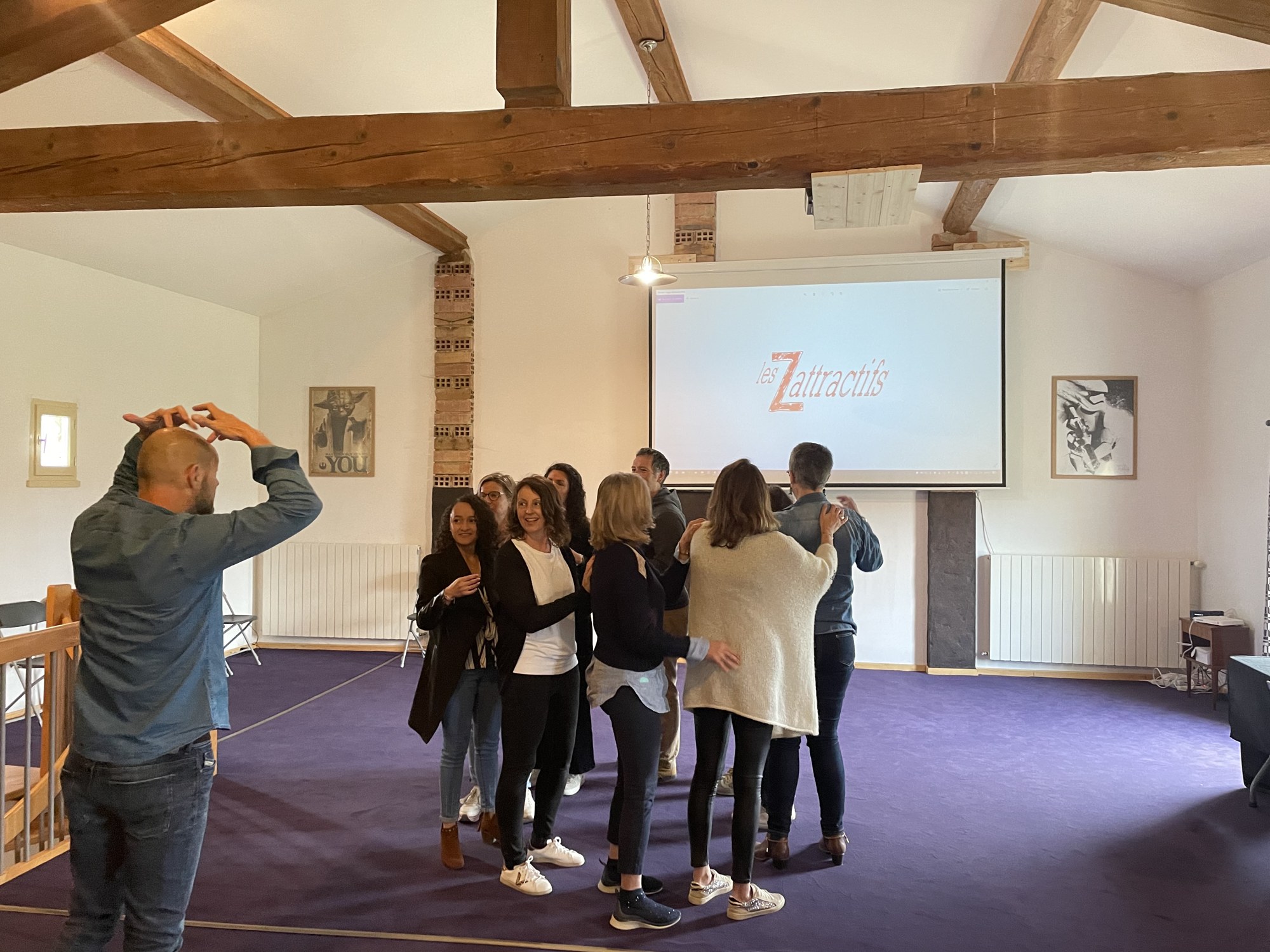 Accolade de groupe, joyeuse et sincère, devant l'écran Les Zattractifs.